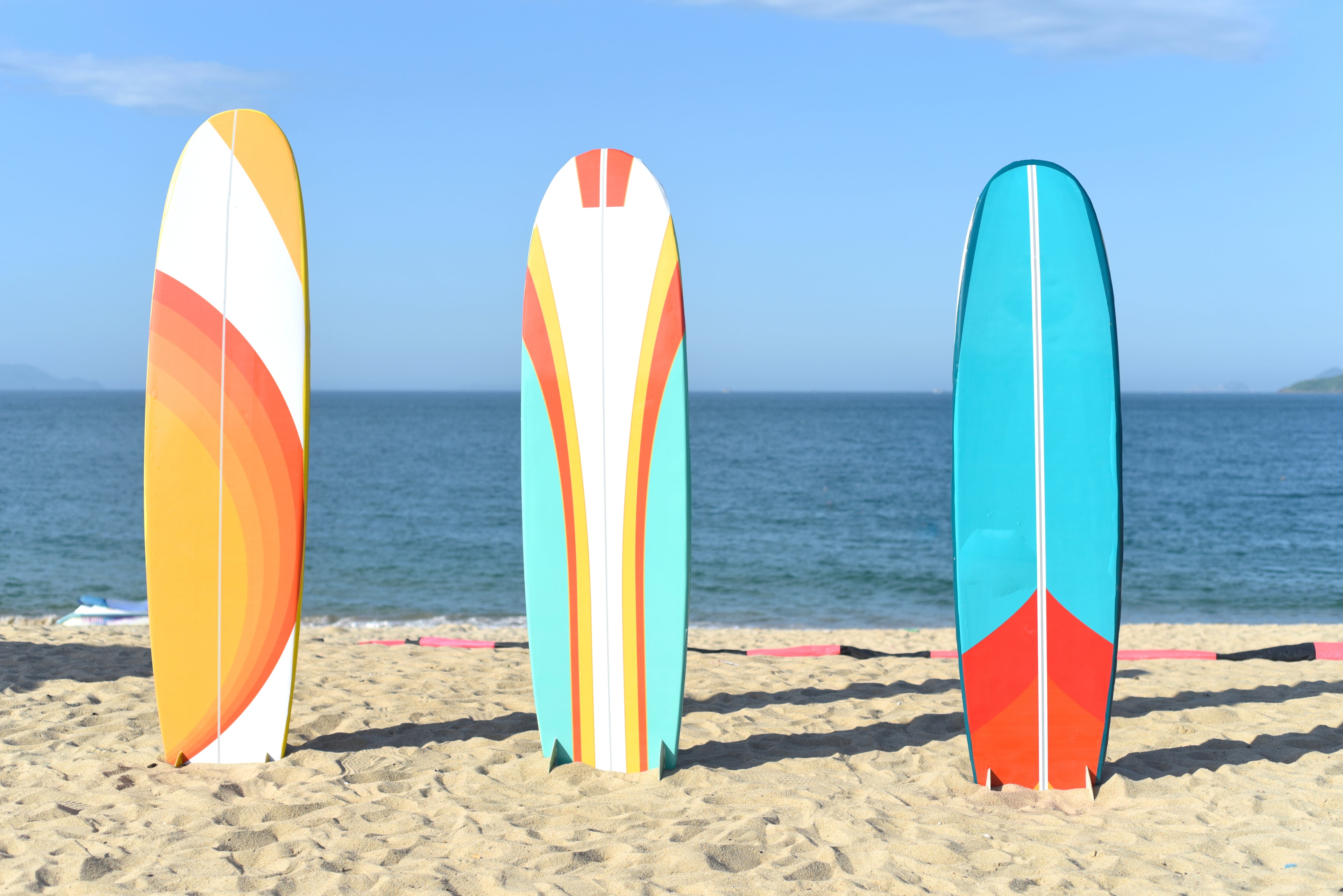 Colourful surfboards lined up on a beach.